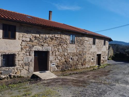 un antiguo edificio de piedra con dos puertas en una carretera en Casa Xulián, en Monterroso