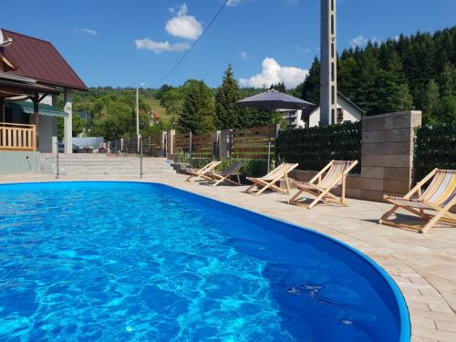 une piscine bleue avec des chaises et une église dans l'établissement Przystanek Letnisko, à Komańcza