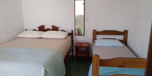 Habitación pequeña con 2 camas y espejo. en Pousada Sítio São Pedro en Delfinópolis