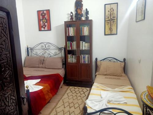 een kamer met 2 bedden en een boekenplank bij Dar 36 LAKSIBA in Marrakesh