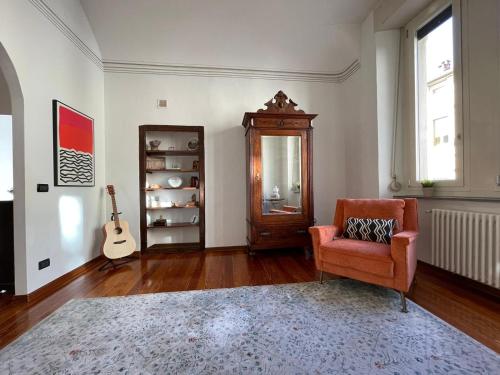 een woonkamer met een stoel en een gitaar bij Large, luxurious family apartment in Biella's historic center in Biella