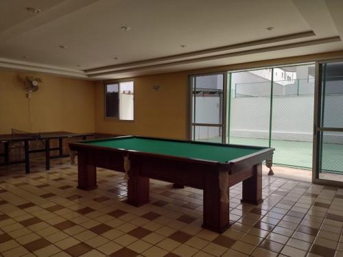 a pool table in a room with a tennis court at Apartamento Praia do Forte Familiar com piscina in Škorak