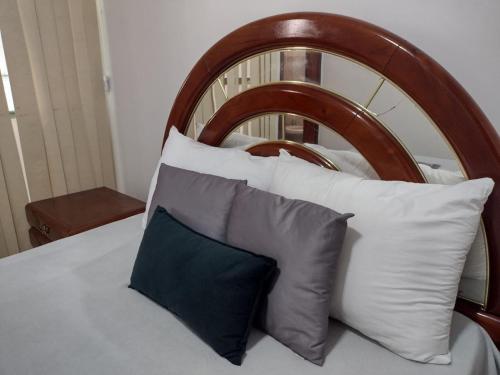 a bed with white pillows and a wooden headboard at Apartamento Praia do Forte Familiar com piscina in Škorak