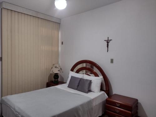 a bedroom with a bed with a cross on the wall at Apartamento Praia do Forte Familiar com piscina in Škorak