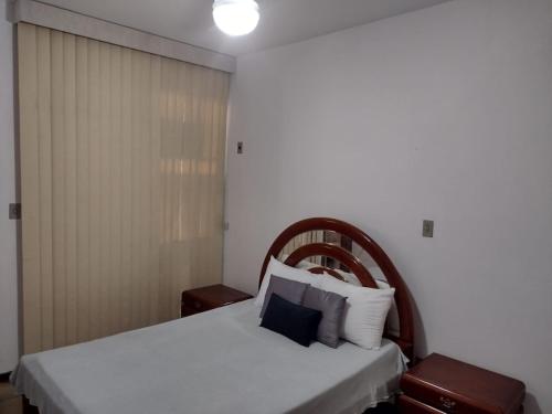 a bedroom with a white bed with a wooden headboard at Apartamento Praia do Forte Familiar com piscina in Škorak