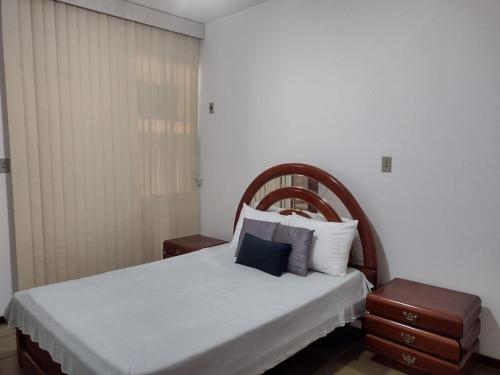 a bedroom with a white bed with a wooden headboard at Apartamento Praia do Forte Familiar com piscina in Škorak