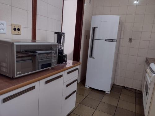 a kitchen with a white refrigerator and a microwave at Apartamento Praia do Forte Familiar com piscina in Škorak