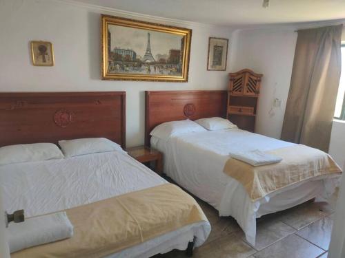 a bedroom with two beds and a picture on the wall at Beautiful Rustic Cottage Adobe, Rancho El Payasito in Cuauhtémoc