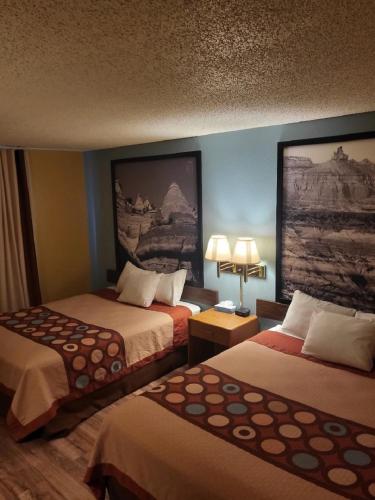 a hotel room with two beds and a painting on the wall at Super 8 by Wyndham Raton in Raton
