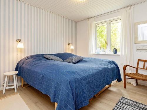 a bedroom with a blue bed and a window at Holiday home Læsø LIII in Læsø