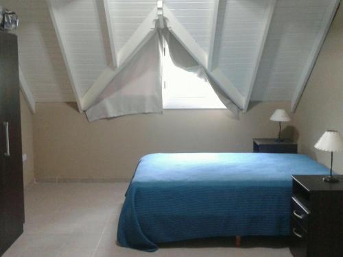 a bedroom with a blue bed and a window at Arenas 497 in Pinamar