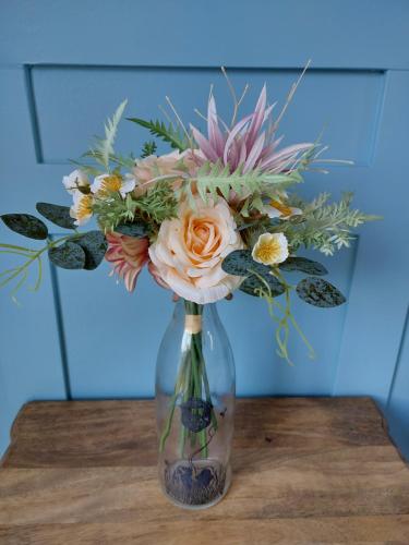a glass vase with a bouquet of flowers on a table at DuxHouse BnB in Taihape