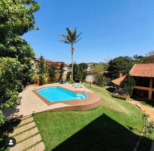 een zwembad in een tuin met een palmboom bij Hotel Chalés Gramado in Águas de Santa Barbara