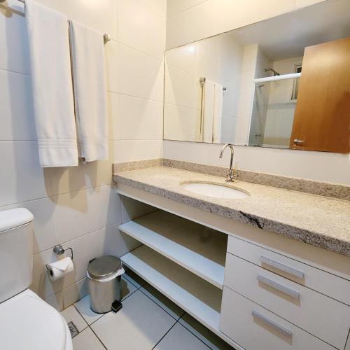 a bathroom with a sink and a toilet and a mirror at Atlantis Residence in Vitória
