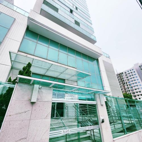 a tall building with glass windows in a city at Atlantis Residence in Vitória