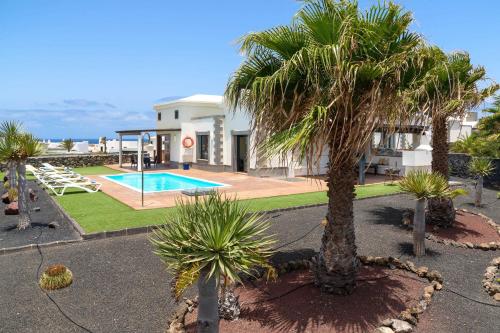 een villa met palmbomen en een zwembad bij Villa Esterlicia in Playa Blanca