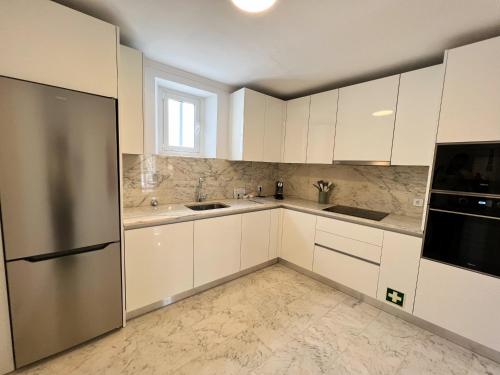 uma cozinha com armários brancos e um frigorífico de aço inoxidável em Madre de Deus, 5 - Terrace em Évora