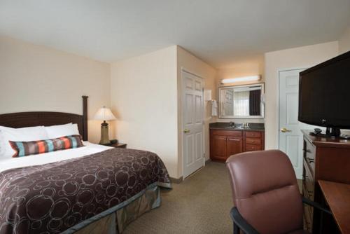 a hotel room with a bed and a flat screen tv at Staybridge Suites Tucson Airport, an IHG Hotel in Tucson