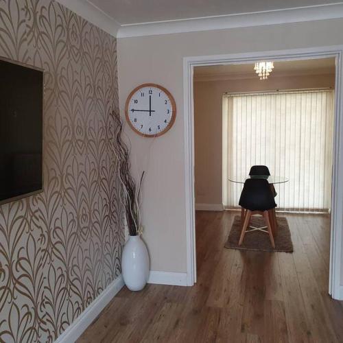 a living room with a clock on the wall and a chair at Ideally located contemporary 3 bed spacious house in Wainscot