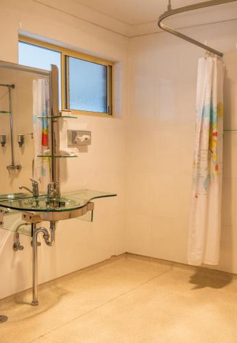 a bathroom with a glass sink and a shower at Golfers Inn in Tenterfield
