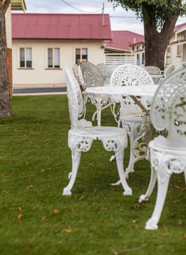 a group of white tables and chairs in a yard at Golfers Inn in Tenterfield