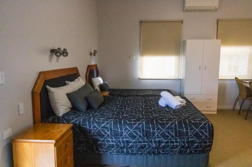 a bedroom with a bed with a blue pillow on it at Golfers Inn in Tenterfield