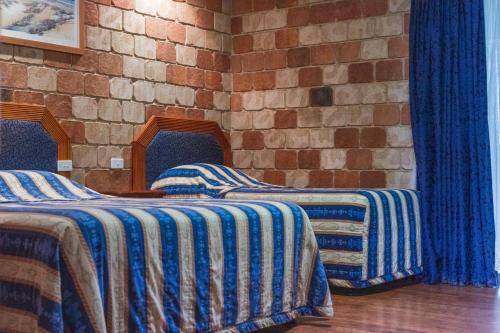 two beds in a room with a brick wall at Golfers Inn in Tenterfield
