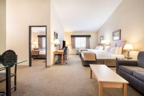 a hotel room with a bed and a living room at Best Western Golden Spike Inn & Suites in Hill City