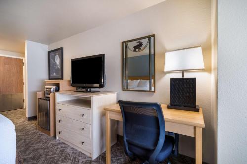 a hotel room with a desk with a television and a chair at Best Western Golden Spike Inn & Suites in Hill City