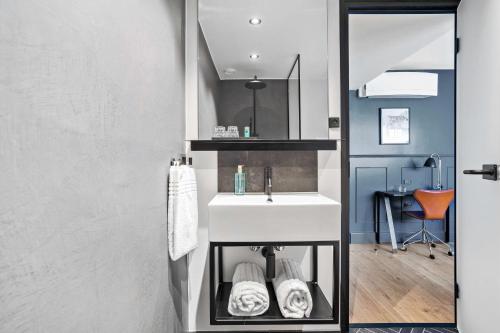 a bathroom with a white sink and a mirror at The Huxley Copenhagen, BW Premier Collection in Copenhagen