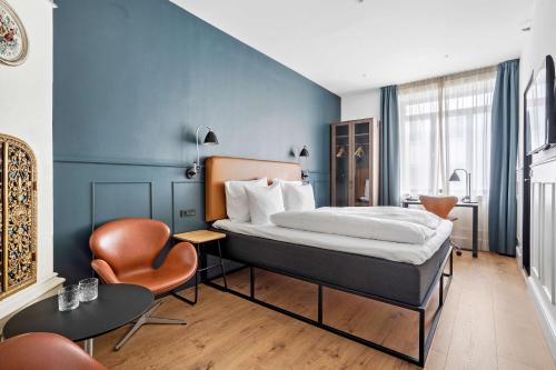 a hotel room with a bed and a chair at The Huxley Copenhagen, BW Premier Collection in Copenhagen