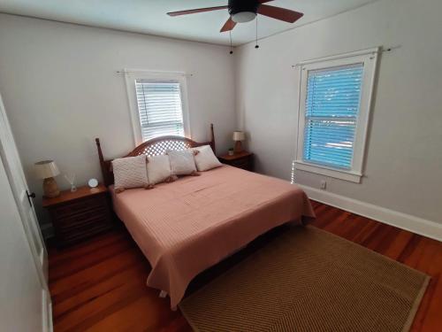 um quarto com uma cama, uma ventoinha e 2 janelas em Beautiful Mid Century Bungalow In The Heart of Lakeland em Lakeland