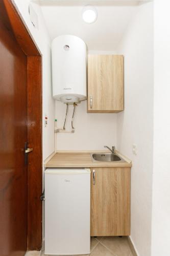 a small kitchen with a sink and a refrigerator at Vila Nikezić in Sutomore
