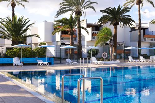 a pool at a hotel with palm trees and umbrellas at Casa Lola in Costa Del Silencio