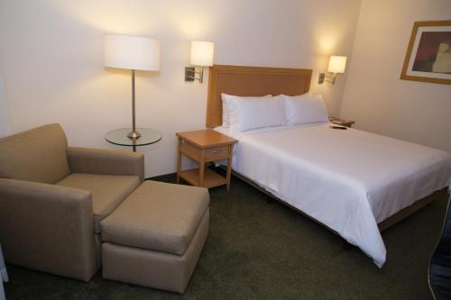 a hotel room with a bed and a chair at Fiesta Inn Ecatepec in Mexico City