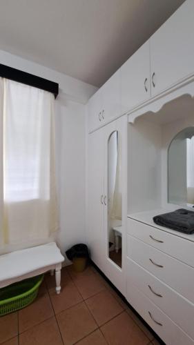 スバにあるMead Road Homestay Tours & Transfers Deluxe Flat 2 Bedroomの白いキャビネットと鏡付きのキッチン