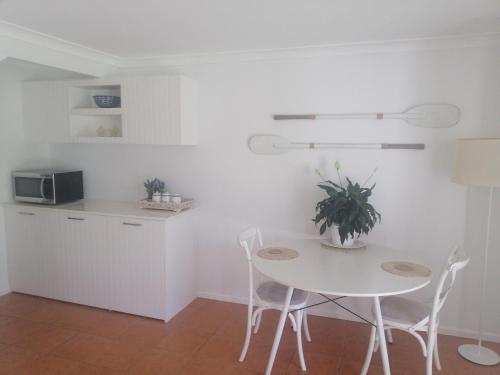 a white kitchen with a table and chairs and a microwave at Sapphire Beach Pet Friendly Beach 5 minute walk in Sapphire Beach