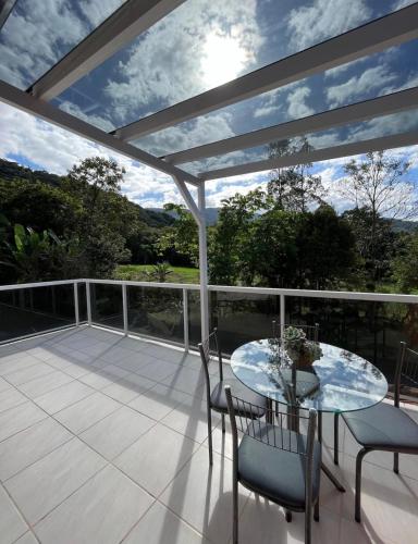 eine Terrasse mit einem Glastisch und Stühlen auf einer Terrasse in der Unterkunft Loft com linda vista na Rota do Enxaimel in Pomerode