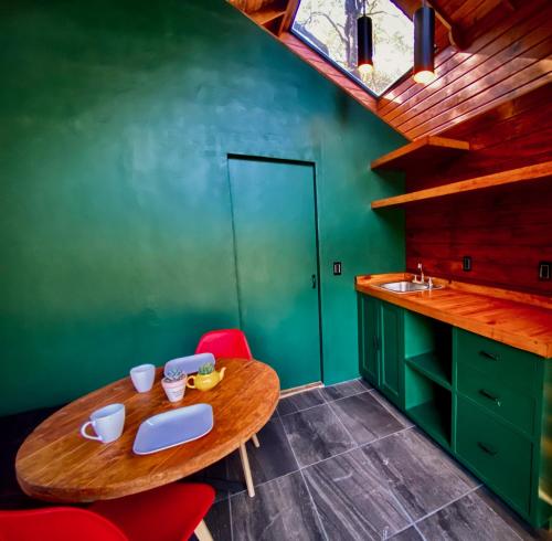 a kitchen with a wooden table and a green wall at Casa Alfeñique in Villa del Carbón