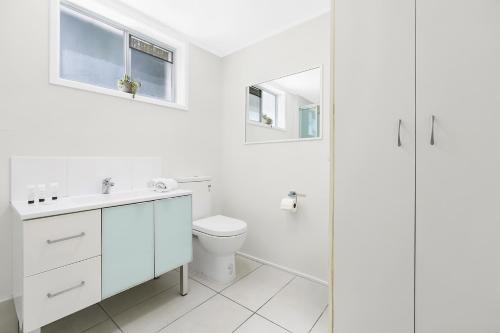 a white bathroom with a toilet and a sink at Ultimate Burleigh Beach House Family Retreat! - 5 BEDROOMS in Gold Coast