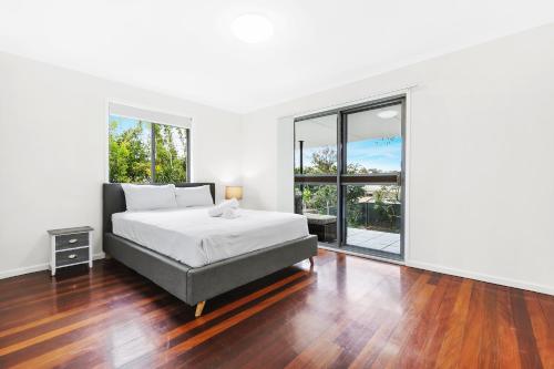 a bedroom with a bed and a large window at Ultimate Burleigh Beach House Family Retreat! - 5 BEDROOMS in Gold Coast