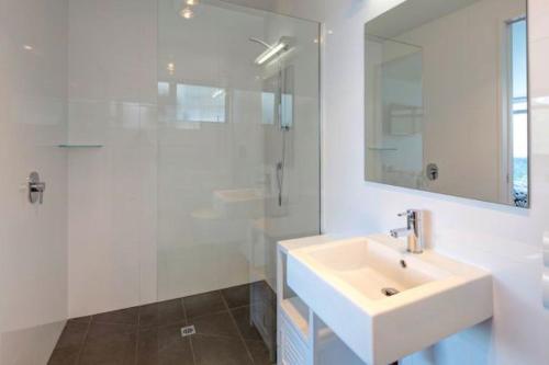 a white bathroom with a sink and a shower at Spectacular Panoramic 5Bedroom Lakeview in Queenstown