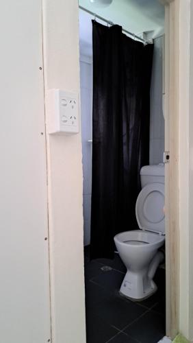 uma casa de banho com um WC e uma cortina de chuveiro preta em Meadroad homestay tours & transfers Studio Flat em Suva
