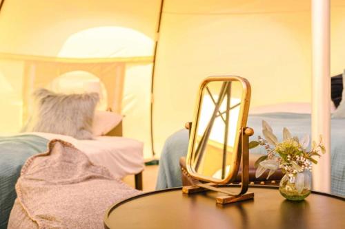 a mirror sitting on top of a table next to a bed at ファームグランピング　ル・クロ　かいづか　いぶきヴィレッジ in Kaizuka