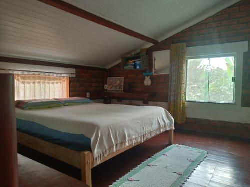 1 dormitorio con 1 cama en una habitación con ventana en Casa Guaiú, en Santa Cruz Cabrália