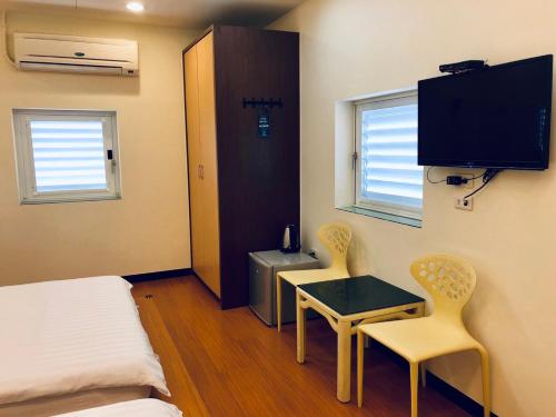 台南的住宿－來七桃旅店，小房间设有一张床、一张桌子和两把椅子