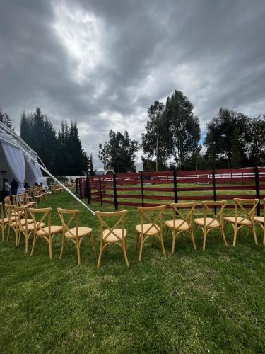 a row of tables and chairs on the grass at Hostería El Troje Experience in Riobamba