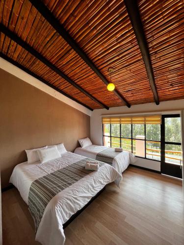 two beds in a bedroom with a wooden ceiling at Hostería El Troje Experience in Riobamba