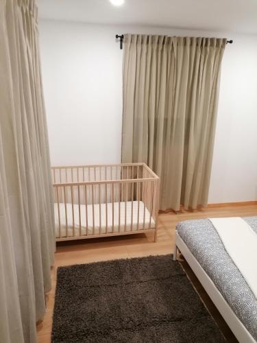 a baby crib in a bedroom with curtains at Casa D'Avó Bina Alojamento Local in Viana do Castelo