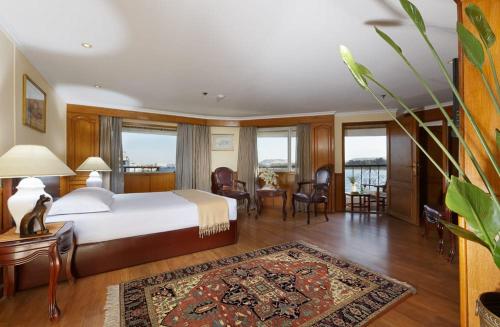 1 dormitorio con 1 cama, mesa y sillas en Nile Cruise 3 nights From Aswan to Luxor Every Friday, Monday and Wednesday with tours en Jazīrat al ‘Awwāmīyah